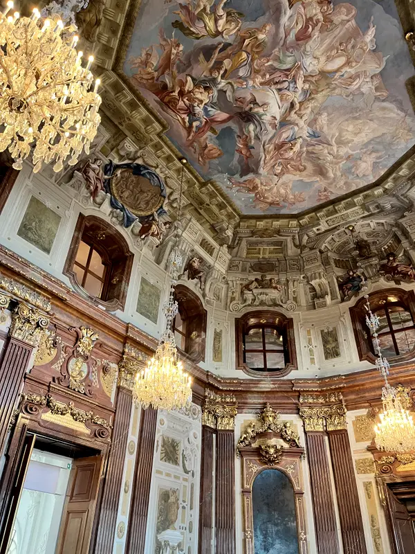 A frescoed ceiling and chandeliers in a Viennese palace interior.