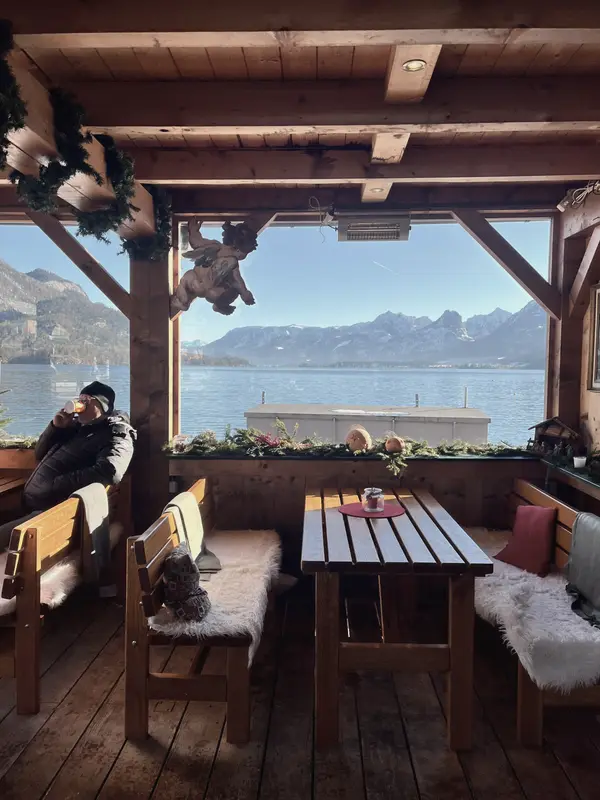 A covered terrace with sheepskins on the benches, lake and mountains beyond.