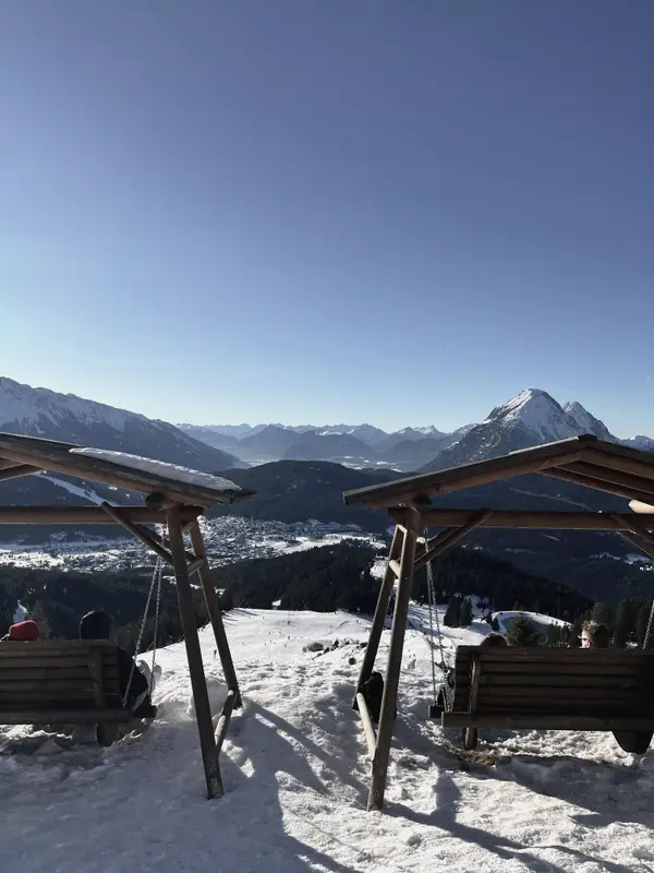 Empty benches under a shelter at the top of the lift, peaks on the far side.