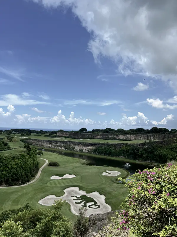 A golf course cut into the green above the coast, cloud stacking up behind.
