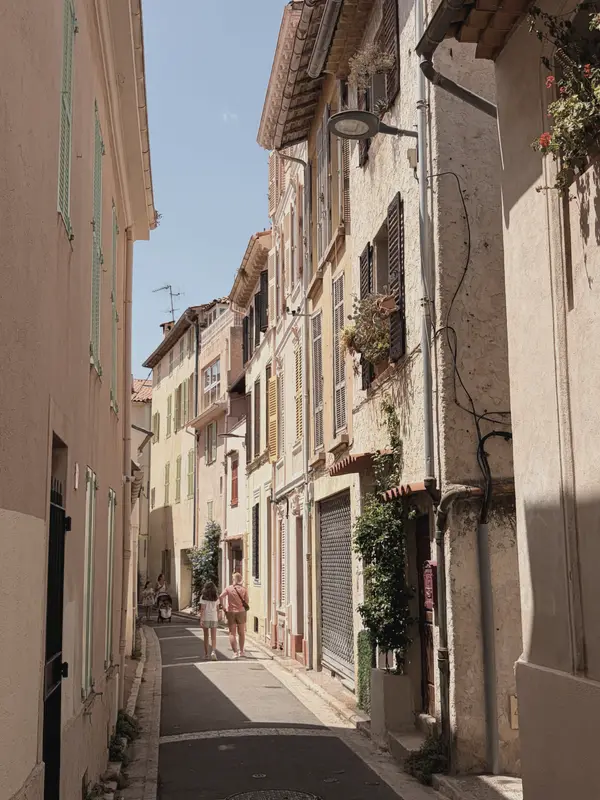 A narrow lane between shuttered houses, washing and vines overhead.