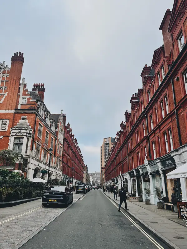 A red-brick London street in Chelsea, shopfronts running down both sides.