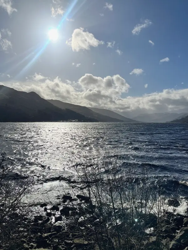 Sun breaking over a Highland loch, wind on the water and hills the far side.