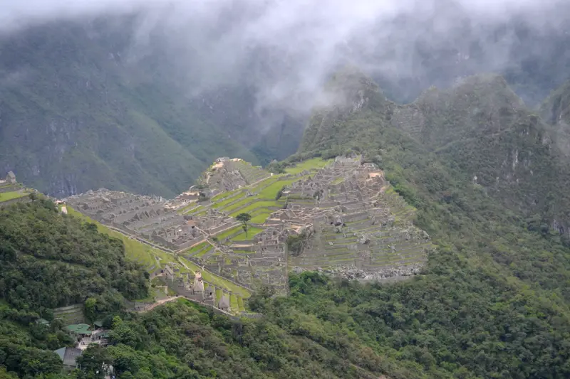 Machu Picchu from above with cloud sitting on the peaks around it.