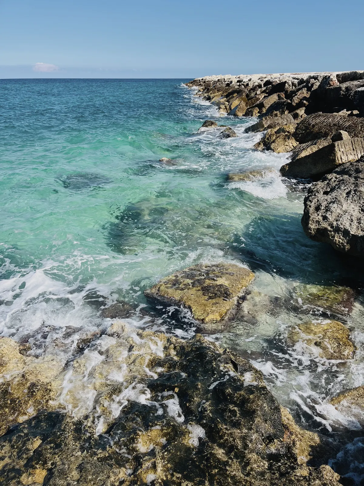 Clear water over rock on the Puglian coast, surf breaking white at the edge.