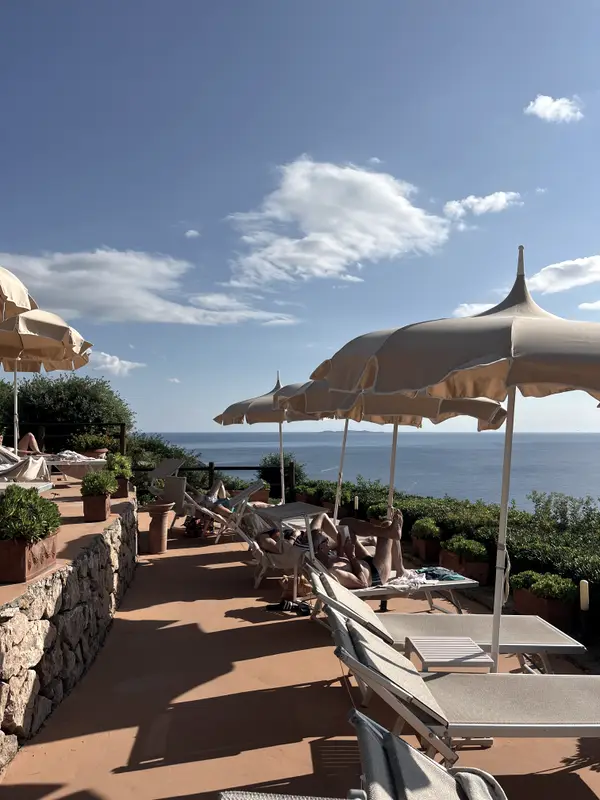 Loungers and umbrellas on a terrace above the sea.