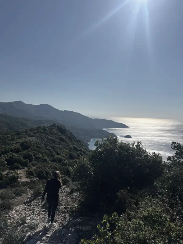A walker on a coast path above the sea at Monte Argentario.