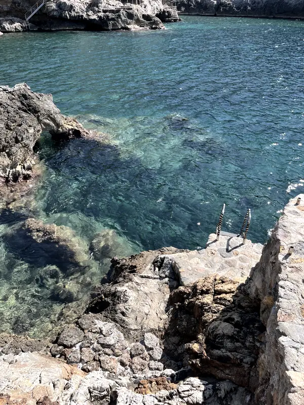 Turquoise water in a rocky inlet, seen from directly above.
