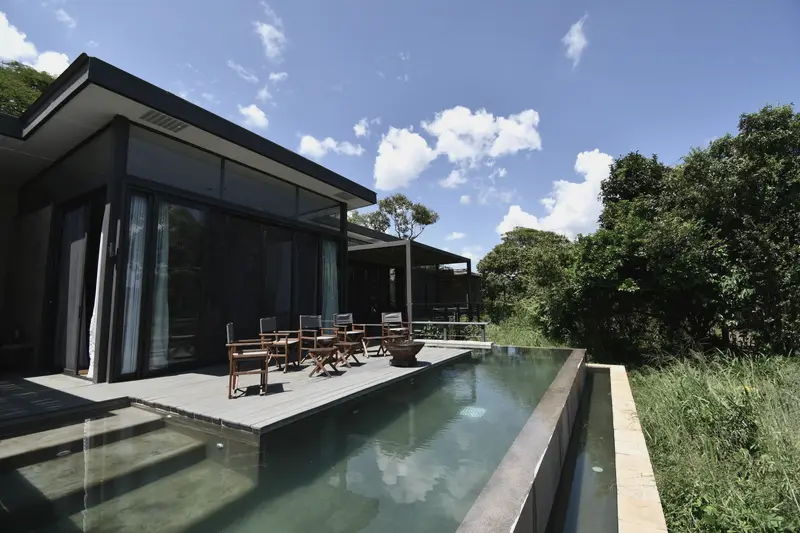A lodge cottage below the Virungas, glass-fronted, with a lap pool running along the deck.