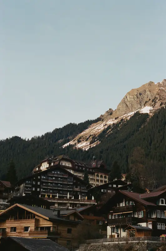 Chalets stacked down the Wengen hillside on film, bare rock and snow behind them.