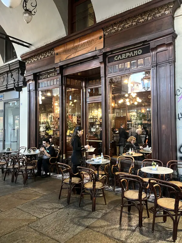A café in Turin under its arcade, tables out on the stone.