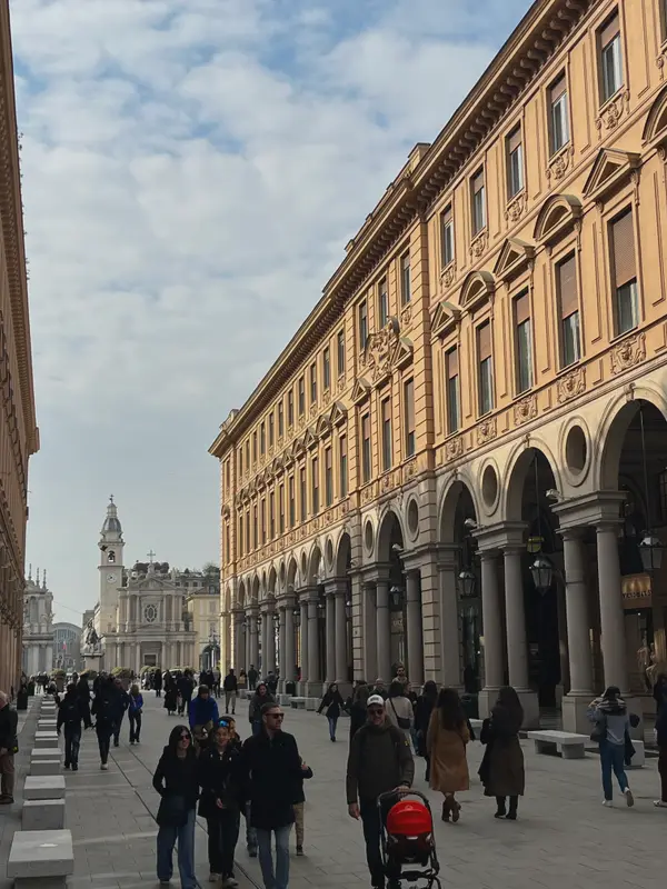 An arcaded street in Turin, people walking the length of it.