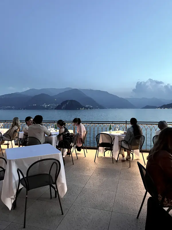 Dinner on a terrace over the lake, tables laid and the far shore going blue.