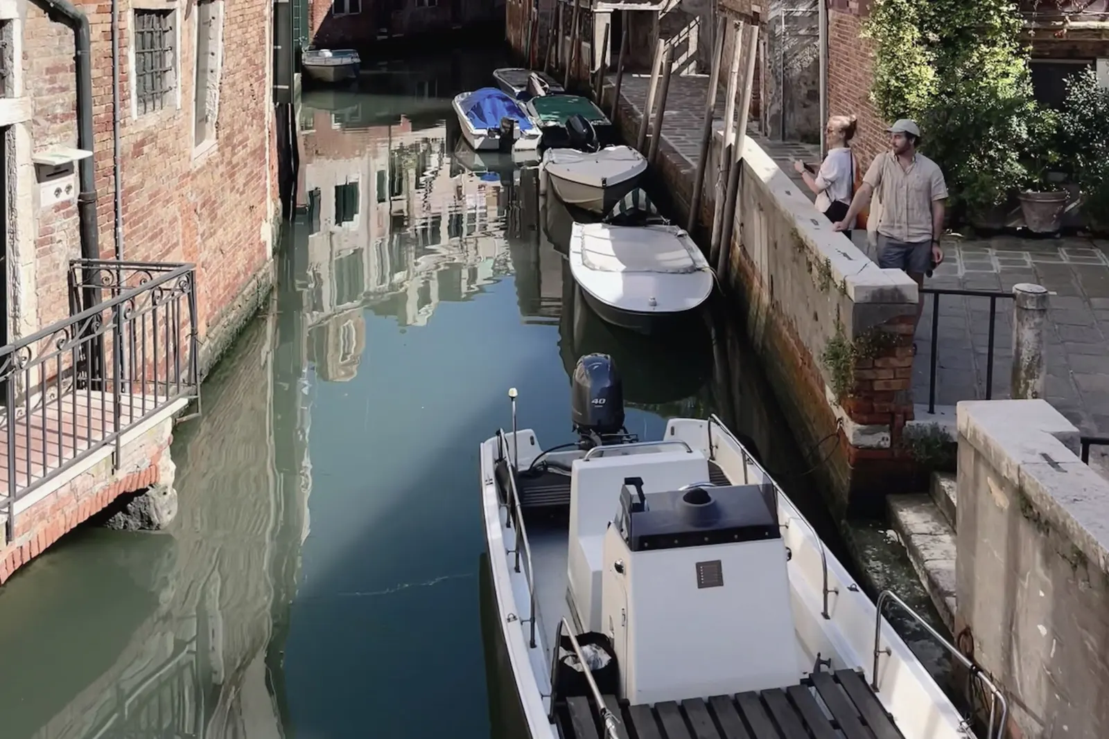 A quiet Venice canal, washing strung between the houses and boats tied along the wall.