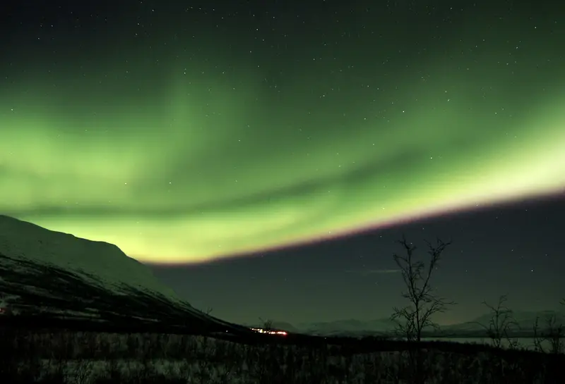 A band of aurora running the length of the valley, hills black underneath.